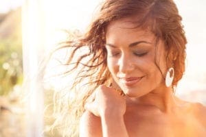 Close up of smiling woman with her hair blowing in the breeze during sunset.